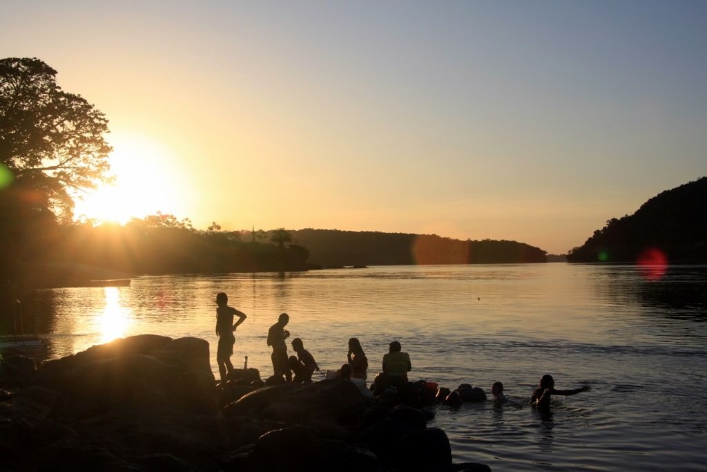 Personas bañándose en el río al atardecer